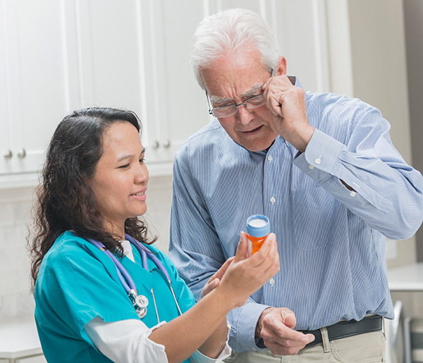 Nurse and man examining prescription bottle